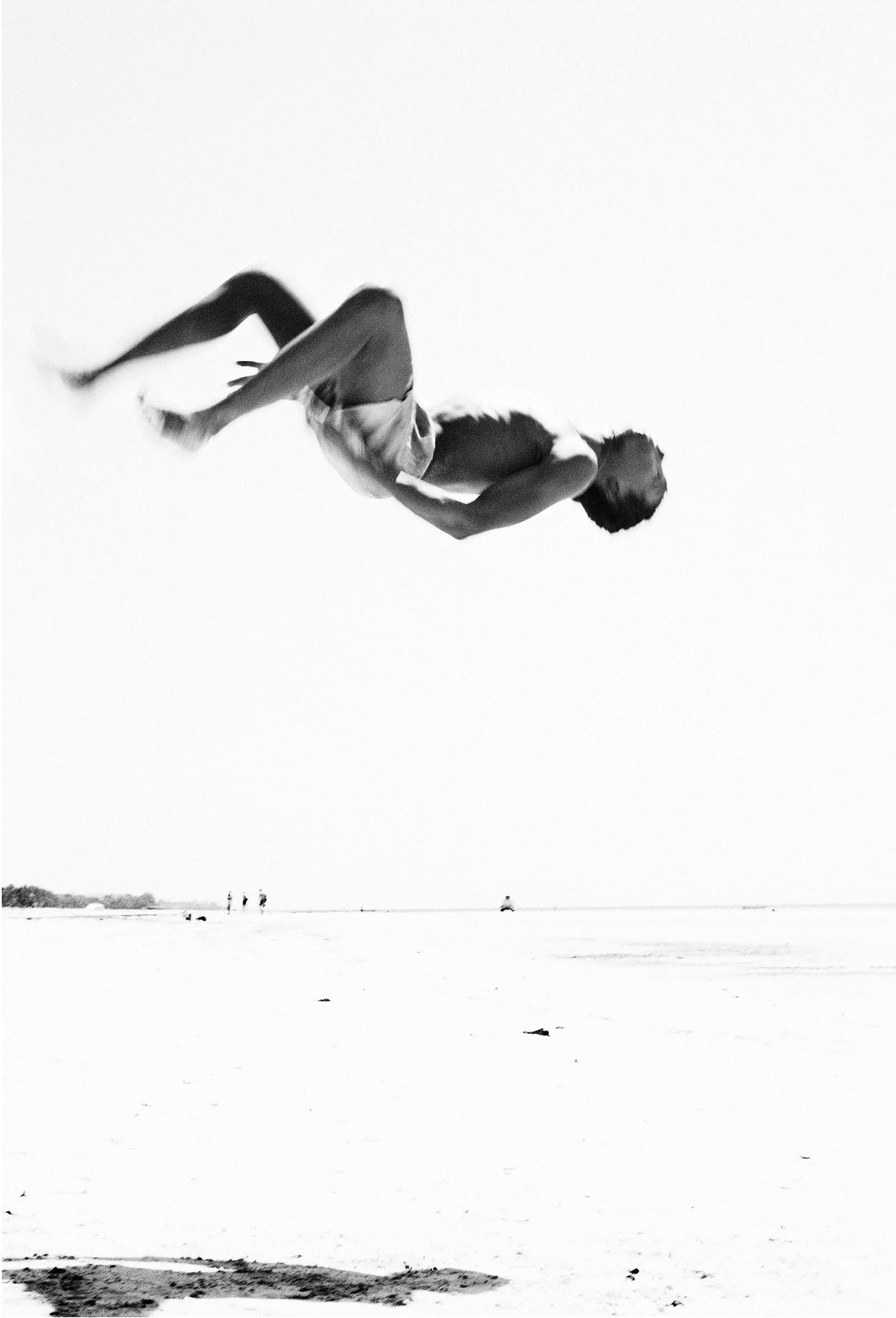 Acrobat mid-air above dunes