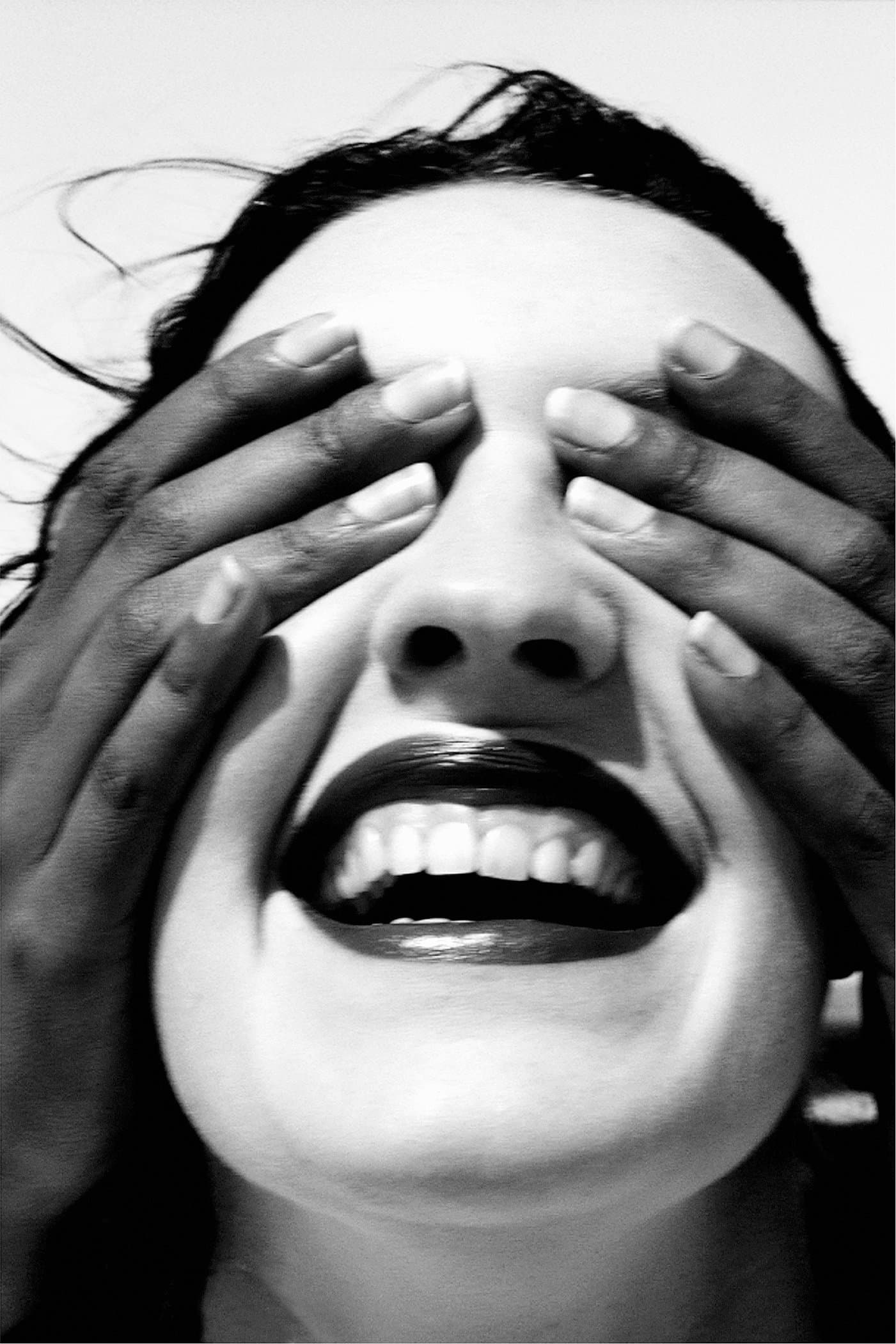 A woman laughing with hands over her eyes